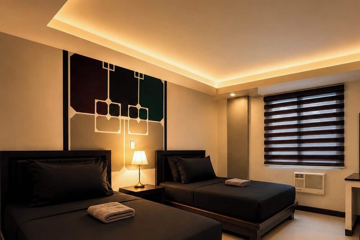 Habitación de hotel con dos camas, aire acondicionado instalado en la pared y una ventana con persianas.