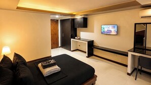 Un dormitorio moderno con cama, mesita de noche, televisor y zona de escritorio.