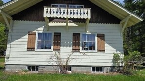 Ein zweistöckiges Haus mit Satteldach, einer Veranda und einem kleinen Vorgarten.