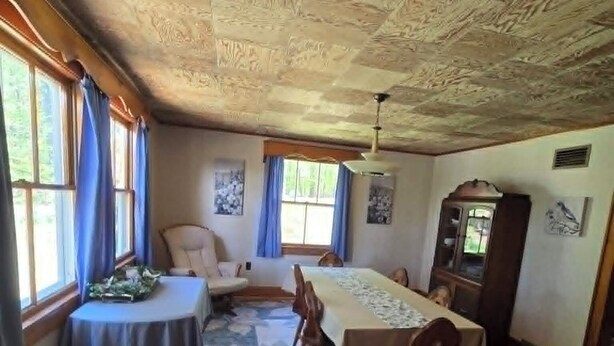 Ein Esszimmer mit Holzbalkendecke, einem großen Tisch und Stühlen.