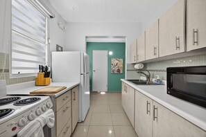 Eine kleine Küche mit Herd, Kühlschrank, Mikrowelle und Spüle.