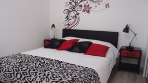 Een net opgemaakt bed met een bedspreide met patroon, een zwart-wit hoofdbord en decoratieve muurkunst.
