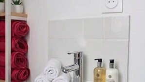 A white sink with a mirror above it, a towel rack with rolled towels, and two toiletries on the counter. - Authentic apartment - Historic Orbec (Orbec)