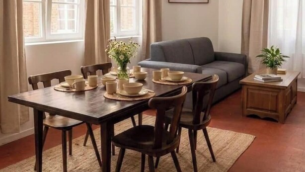 A dining area with a table set for four, a sofa, a hanging light fixture, and a framed picture on the wall. - Authentic apartment - Historic Orbec (Orbec)