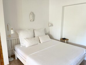 Ein Schlafzimmer mit Bett, Nachttischlampen, einem Nachttisch und einer Wandleuchte.