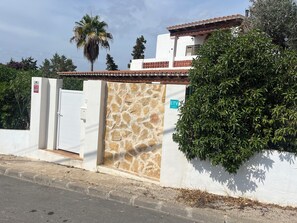 A gated property with a stone wall, a white building with a tiled roof, and a sign indicating an ETV service.