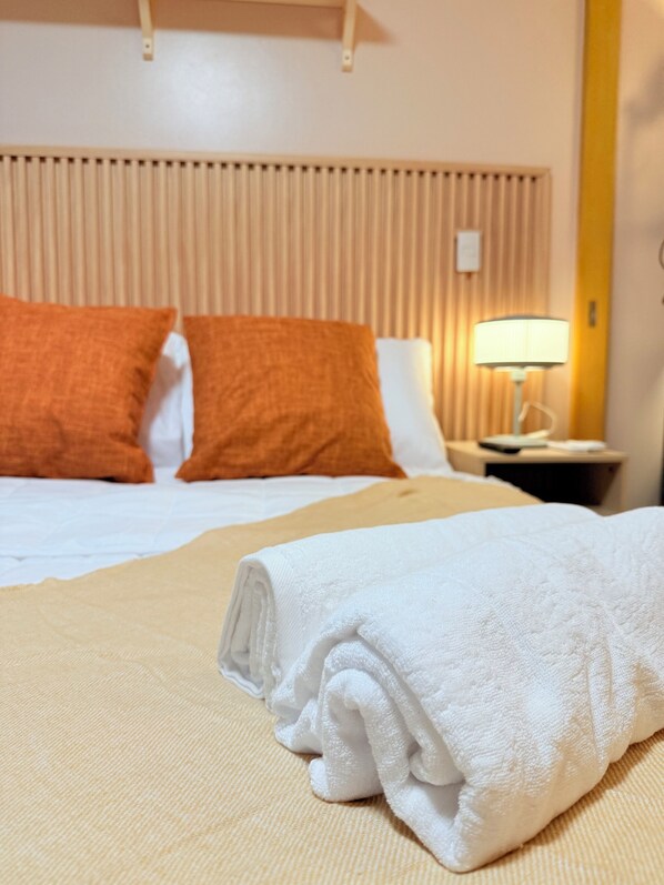 A hotel room with a bed, pillows, a nightstand, and a lamp. - NEW! Modern & Cozy Space in Uptown BGC, Taguig near mall BackHome2 (Taguig)
