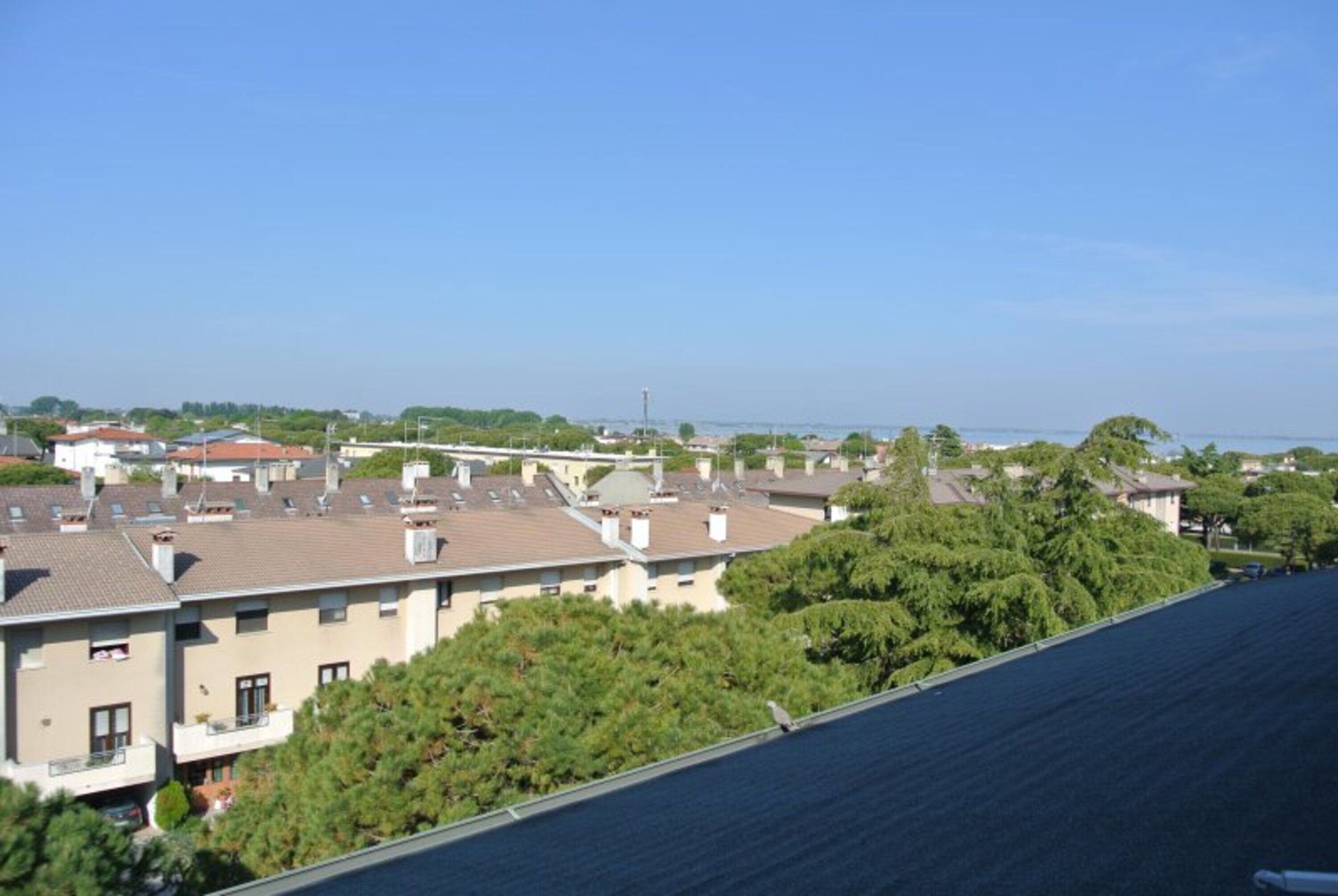 Un quartier résidentiel composé de plusieurs immeubles à deux étages, avec un ciel dégagé et une vue lointaine sur la mer.