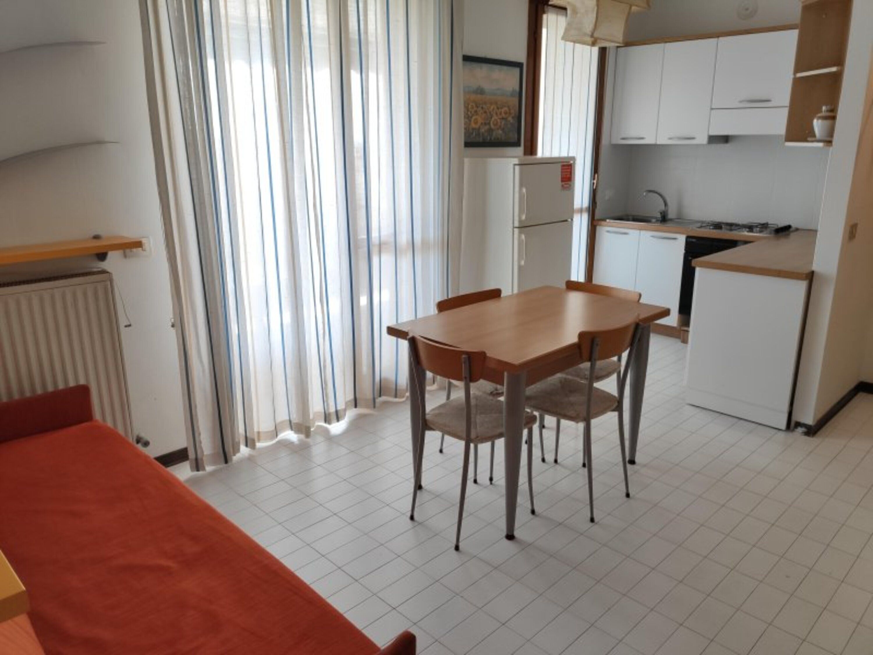 Uma cozinha compacta com mesa e cadeiras, geladeira e um balcão pequeno.