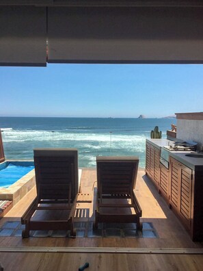 A poolside area with two lounge chairs, a small pool, and a view of the ocean. - Oceanview 2BR & Terrace in Punta Hermosa (Punta Hermosa)