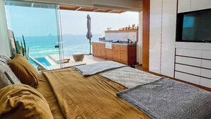 Ein Schlafzimmer mit einem großen Bett, einem Fernseher und Meerblick.