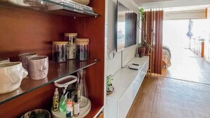 Eine moderne Küche mit Holzregalen, einem Fernseher und Blick ins Freie.