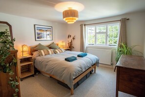 A bedroom with a bed, bedside lamps, a window, and a radiator. - Cosy Sussex Cottage (Robertsbridge, Staplecross)
