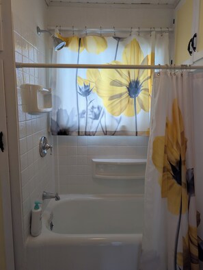 Ein Badezimmer mit einer Badewanne, einer Duschbrause, einem Handtuchhalter und einem Seifenspender.