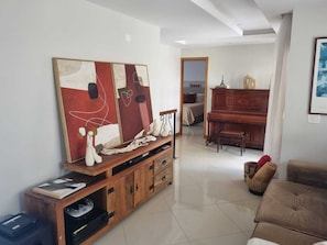 Ein Wohnzimmer mit einem großen abstrakten Gemälde, einer Holz-Unterhaltungsecke, einem Klavier und einem Sofa.