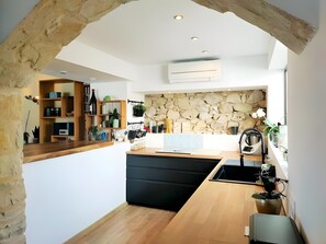 Eine moderne Küche mit Steinwand, Holzregalen und einer schwarzen Arbeitsplatte.