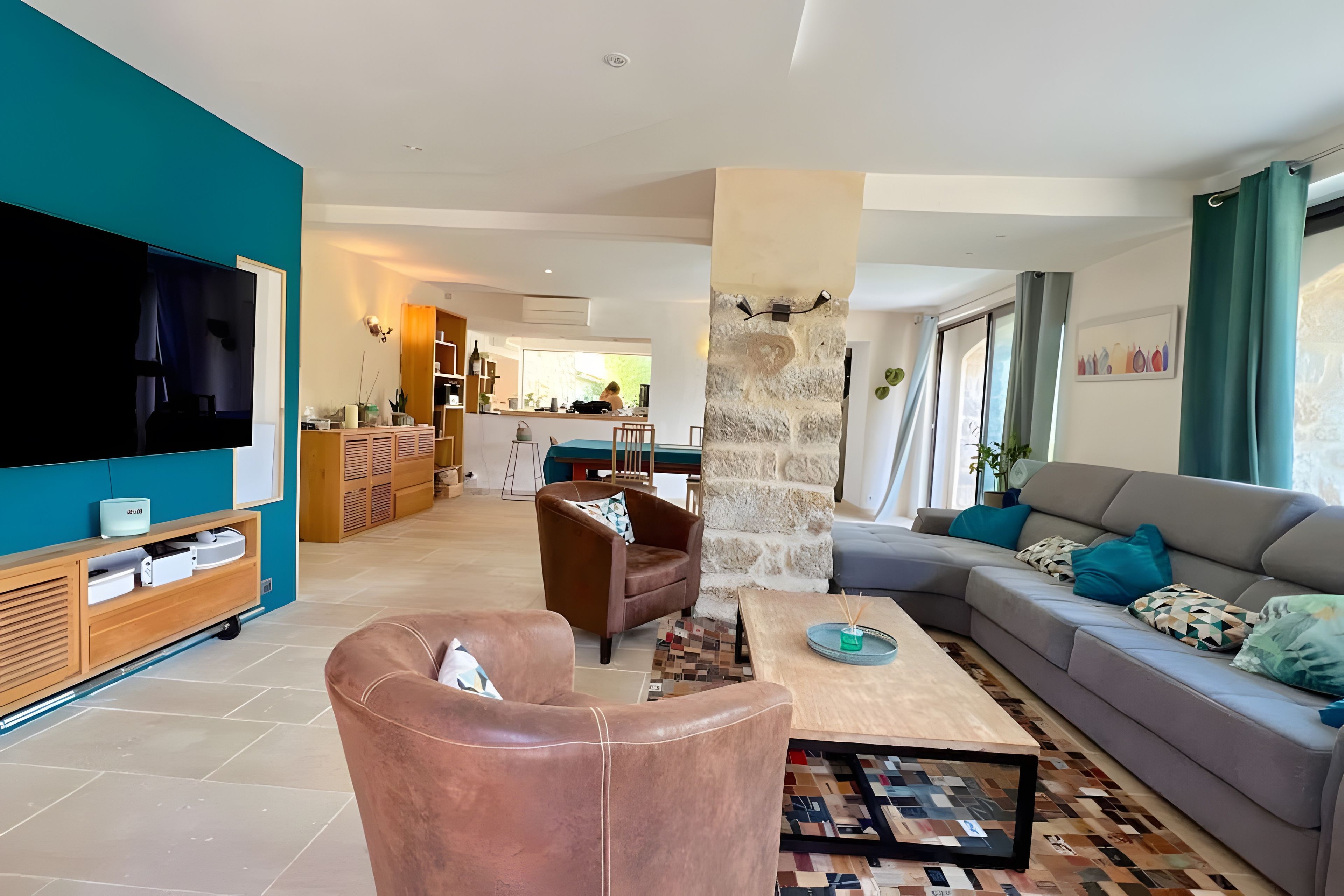 A modern living room with a flat-screen TV, leather armchair, sofa, and a coffee table with a mosaic tile runner.