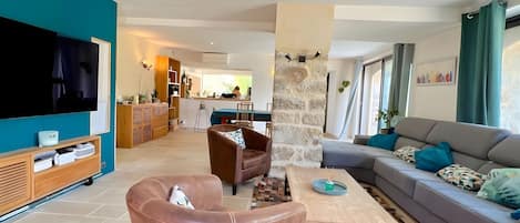 Una sala de estar moderna con televisor de pantalla plana, sillón de cuero, sofá y una mesa de centro con un tapete de mosaicos.