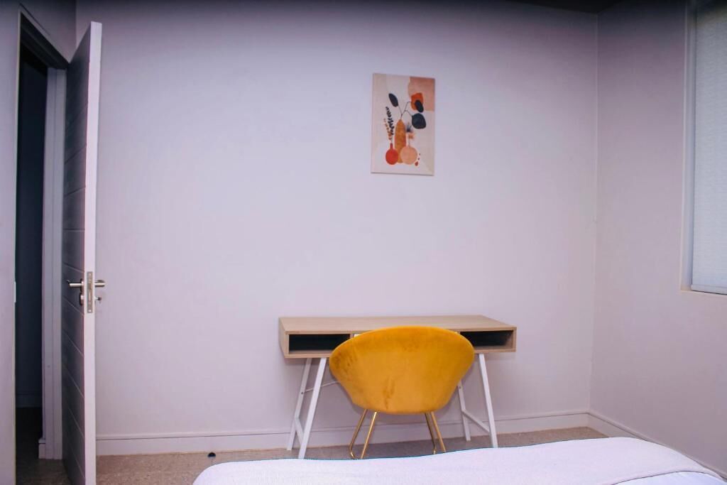 A room with a bed, a desk, a chair, and a wall-mounted artwork.