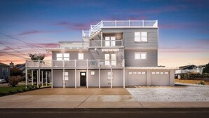 A two-story house with a balcony, a garage, and a driveway. - Amazing Luxury LBI Beach House - Rooftop Bay Views - Walk to Beach - Sleeps 14 (Ship Bottom)