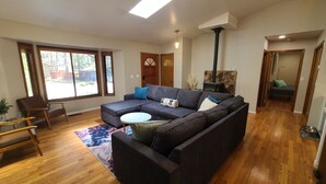 Un salon moderne avec un canapé d’angle, un plancher en bois, une lucarne et une cheminée.