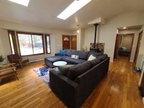 A modern living room with a sectional sofa, wooden flooring, a skylight, and a fireplace. - New! Starlight Pines! Grill/AC/Dog Friendly! (Flagstaff)