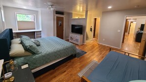 Une chambre à coucher avec un lit, un bureau, une télévision et un ventilateur de plafond.