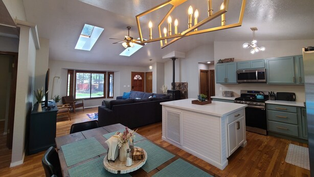 Un vaste espace de vie comprenant un canapé, une table à manger, une cuisine et un ventilateur de plafond.