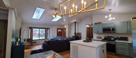 Un espacio habitable amplio con sofá, mesa de comedor, cocina y ventilador de techo.