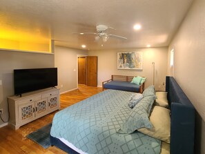Une chambre à coucher avec un lit, une télévision, un ventilateur de plafond et une porte.