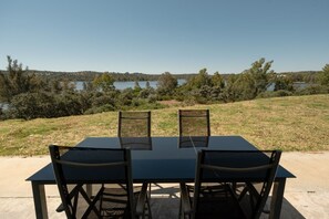 Une table d’extérieur avec quatre chaises, une vue dégagée sur un lac et des arbres tout autour.