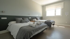 Une chambre avec deux lits, une fenêtre et un luminaire fixé au mur.
