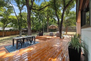 Una terrassa de fusta amb una taula i cadires, envoltada d'arbres.