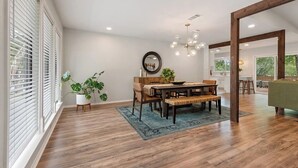 A dining area with a wooden table, chairs, a mirror, and a chandelier. - Near Downtown, 4BR, Austin Heart, Large Backyard (Austin)