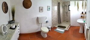 Une salle de bain équipée de toilettes, d’une douche, d’un lavabo et agrémentée d’éléments décoratifs sur le mur.