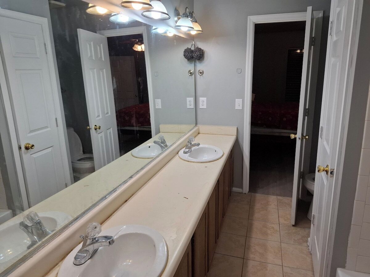 A bathroom with two sinks, a large mirror, and a light fixture above the mirror.