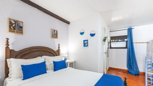 A hotel room with a wooden bed, white walls, and a blue curtain.