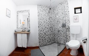 A bathroom with a tiled shower, a sink with a mirror, and a toilet. - Studio Apartment 'S5 - Suite Double Com Kitchenette' with Shared Terrace, Shared Garden and Wi-Fi (Santo António da Charneca)