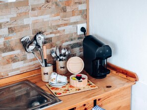 A kitchen counter with a coffee maker, utensils, and a fruit basket. - Studio Apartment 'S5 - Suite Double Com Kitchenette' with Shared Terrace, Shared Garden and Wi-Fi (Santo António da Charneca)