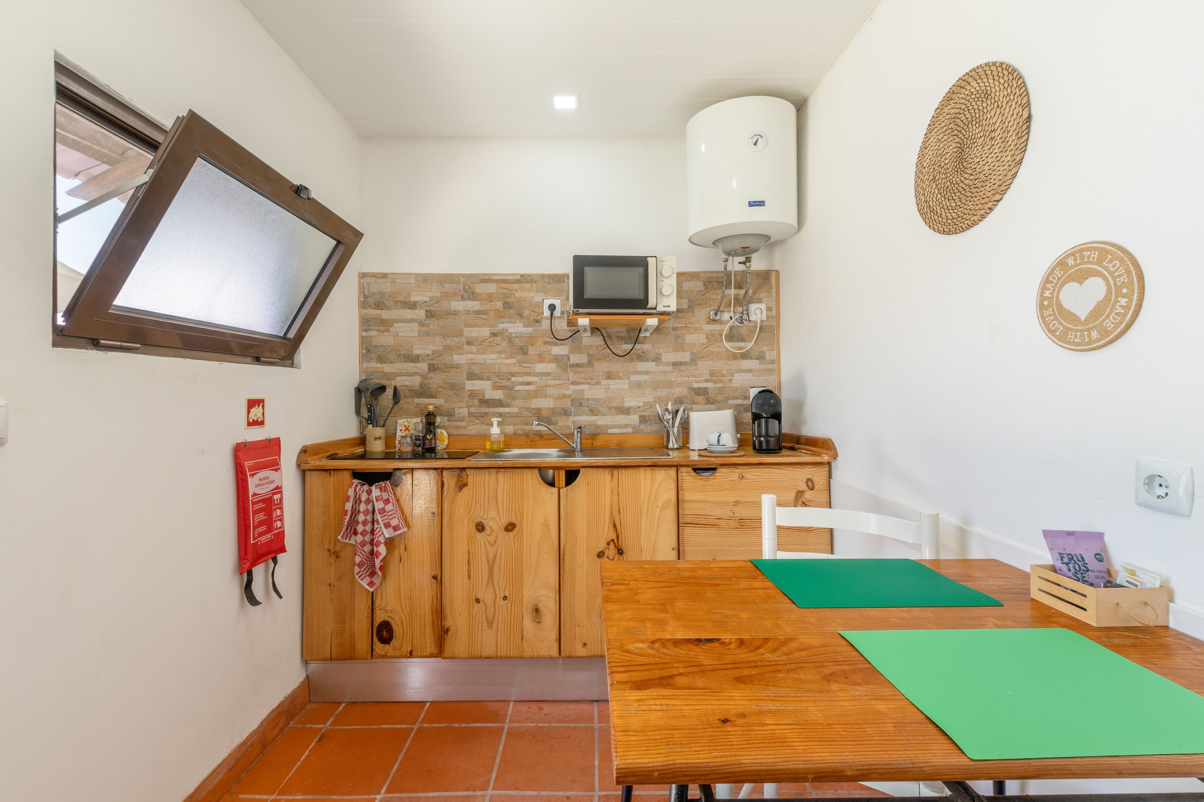 A compact kitchen with a built-in microwave, a water heater, and a small sink.