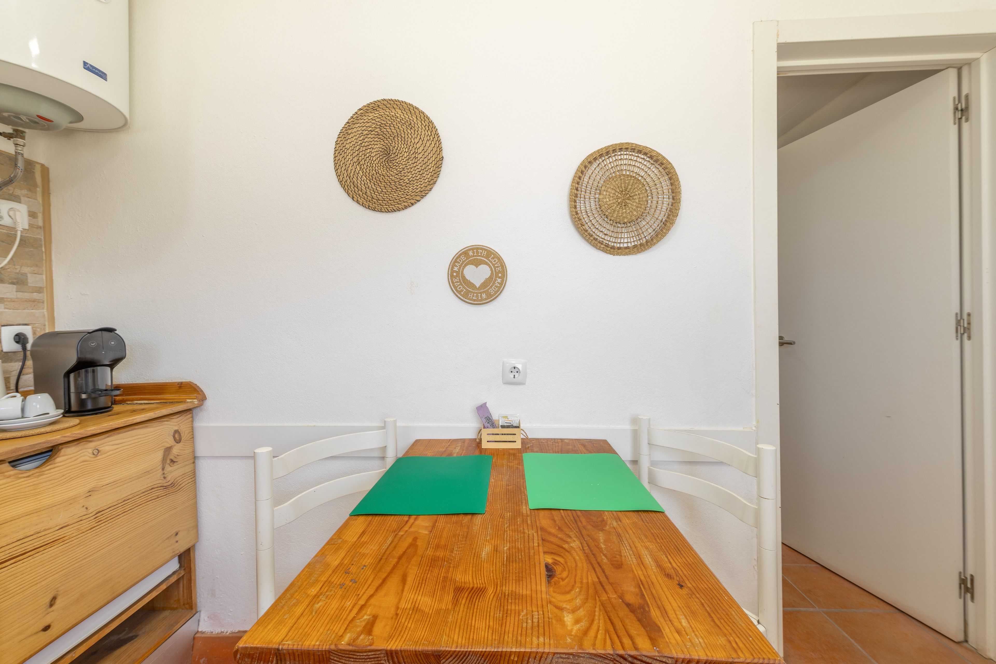 Un petit coin repas avec une table en bois, des chaises blanches et une machine à café.