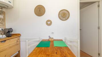 Un petit coin repas avec une table en bois, des chaises blanches et une machine à café.