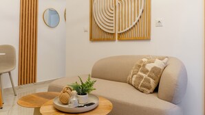 Uma sala de estar moderna com um sofá, uma mesa de centro redonda e arte decorativa na parede.