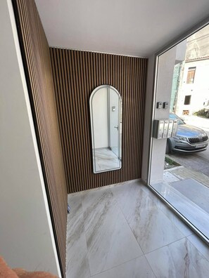 Ein modernes Interieur mit einem großen Spiegel, einer Wand aus Holzpaneelen und Blick auf eine Straße.