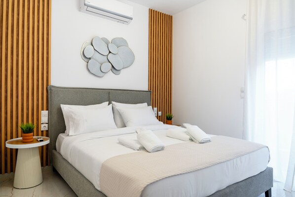 Ein modernes Hotelzimmer mit einem großen Bett, einem runden Beistelltisch, einer Wandklimaanlage und einem Wandbild.