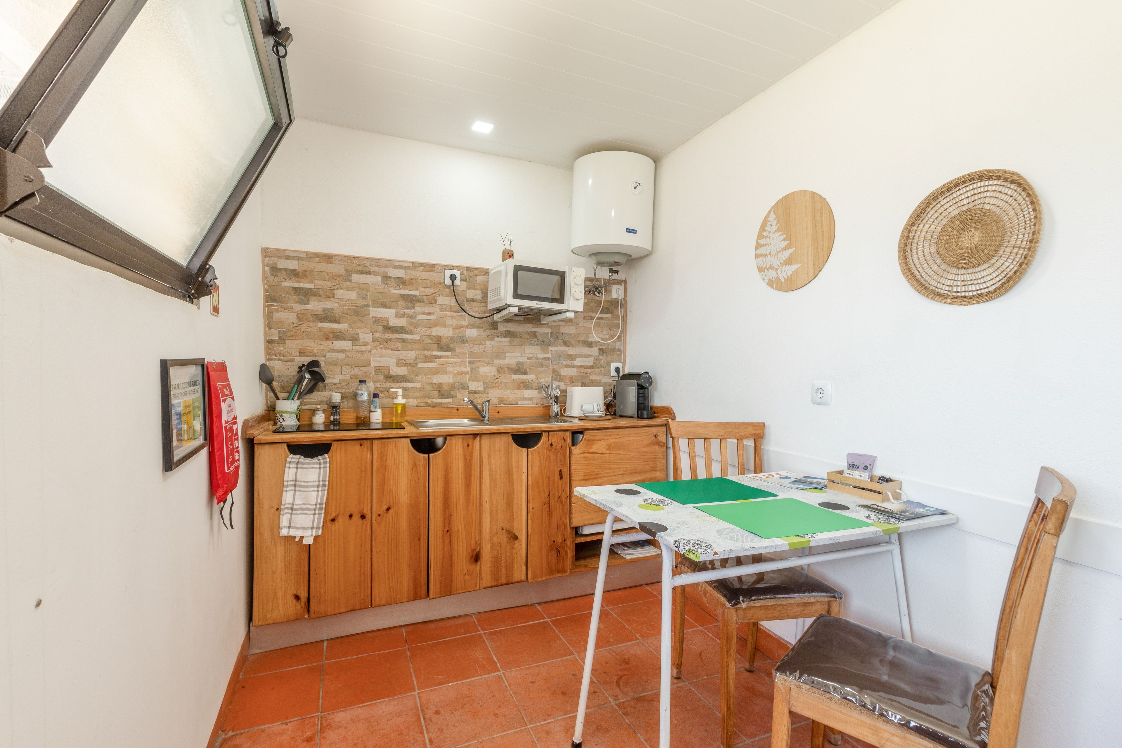 Une cuisine compacte avec des meubles en bois, un four à micro-ondes encastré et une petite table à manger avec des chaises.