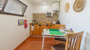 Une cuisine compacte équipée d’un four à micro-ondes, d’un chauffe-eau et d’une petite table à manger avec des chaises.