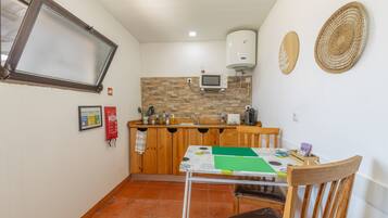 A compact kitchen with a microwave, a water heater, and a small dining table with chairs.