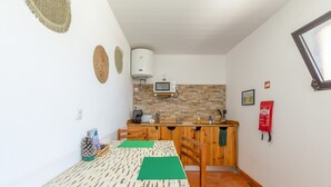 A compact kitchen with a microwave, sink, and wooden cabinets. - Vila Natura – Secret Retreat S4 with Shared Terrace & Garden, Wi-Fi (Santo António da Charneca)