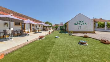A courtyard with outdoor seating, a sign reading 'Vila Natura,' and a well-maintained lawn.